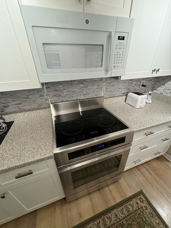 3 Beal's Cove Road, Unit H Hingham, MA 02043 - Photo 3 of 13 a kitchen with granite countertop white cabinets and stainless steel appliances