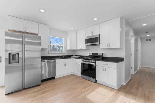 a kitchen with stainless steel appliances granite countertop a stove a sink and a refrigerator