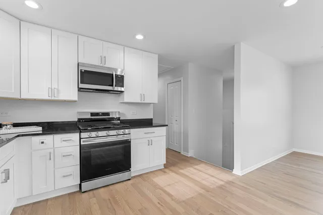 a kitchen with stainless steel appliances granite countertop a stove a microwave and a hard wood floors