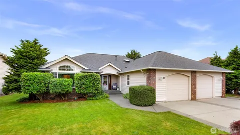 a view of a house with a yard plants and large tree