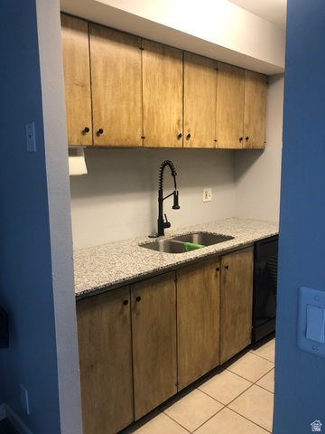88 West 50 South, Unit B5 Centerville, UT 84014 - Photo 12 of 33 Kitchen featuring light stone counters, black dishwasher, light tile patterned floors, and brown cabinetry