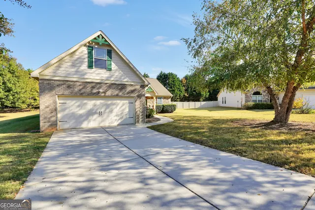 a view of a house with a yard and large tree