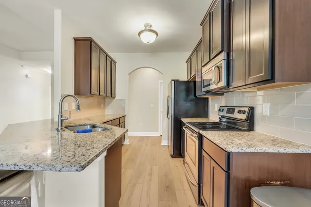 a kitchen with granite countertop stainless steel appliances a sink stove refrigerator and cabinets