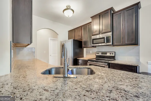 a kitchen with stainless steel appliances granite countertop a refrigerator and a sink