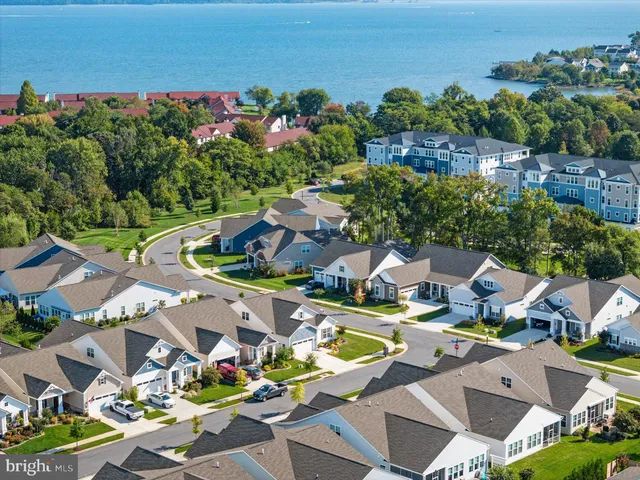 a kitchen with stainless steel appliances granite countertop a refrigerator a stove top oven a sink dishwasher a dining table and chairs with wooden floor