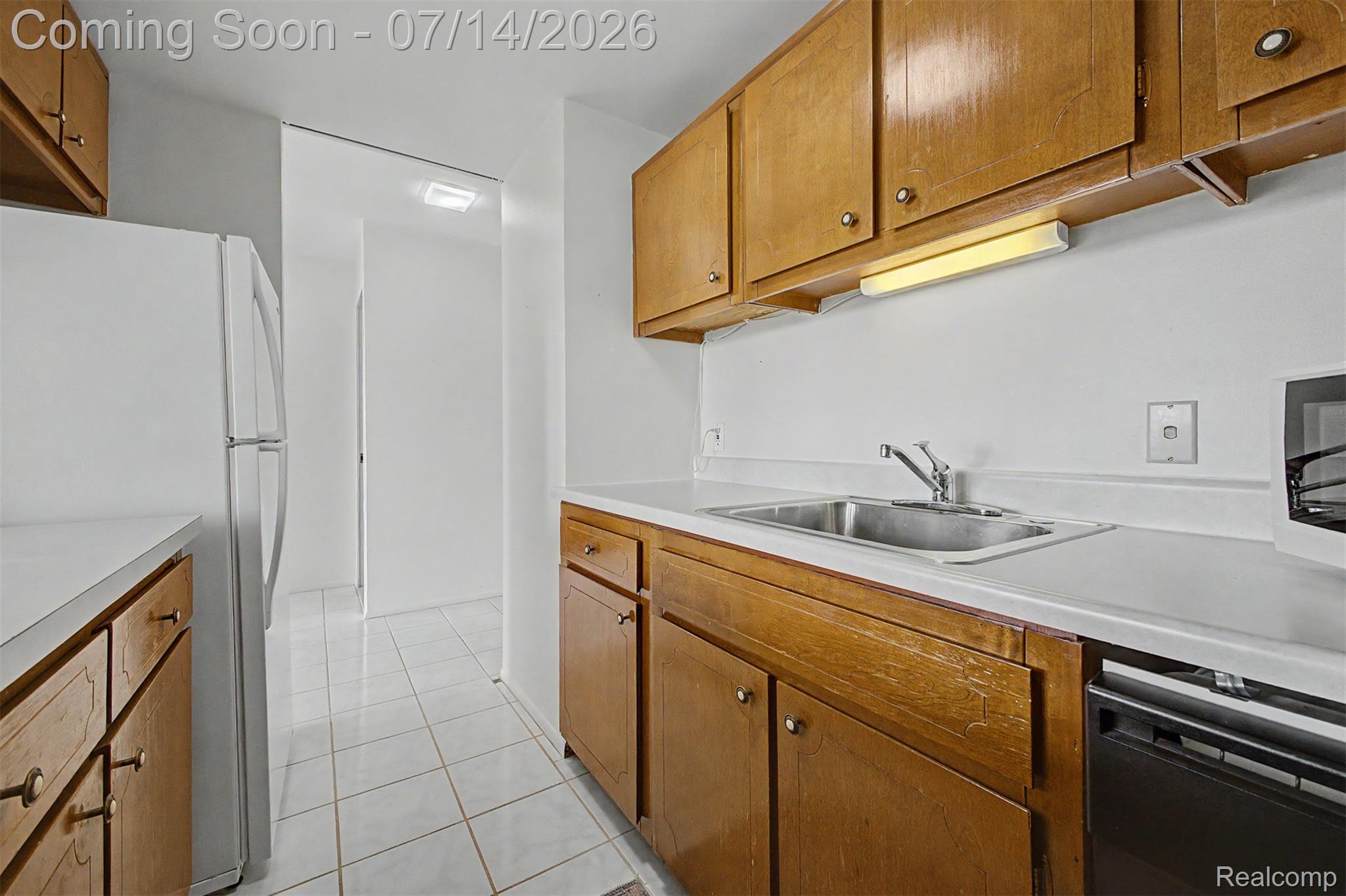 22700 Garrison Street, Unit 707 Dearborn, MI 48124 - Photo 10 of 22 Kitchen featuring wood cabinetry, white countertops, a stainless steel sink, and white tile flooring