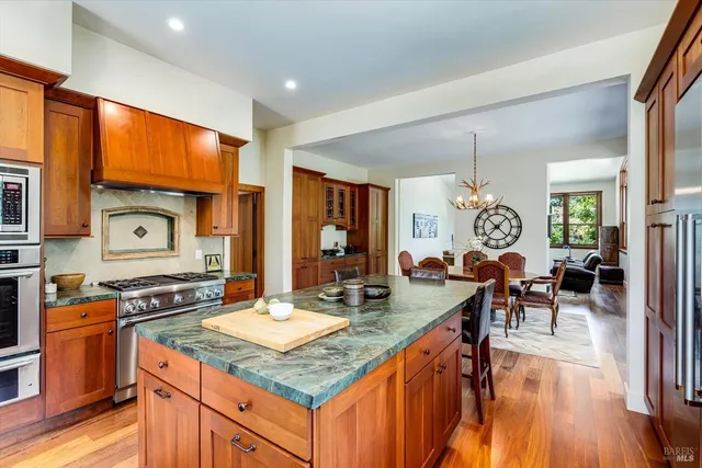 a open kitchen with stainless steel appliances granite countertop a stove top oven a sink dishwasher and couches with wooden floor