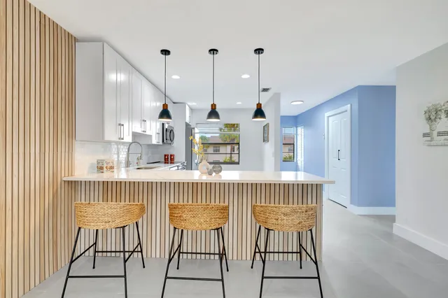 a kitchen with stainless steel appliances kitchen island granite countertop a dining table chairs and white cabinets