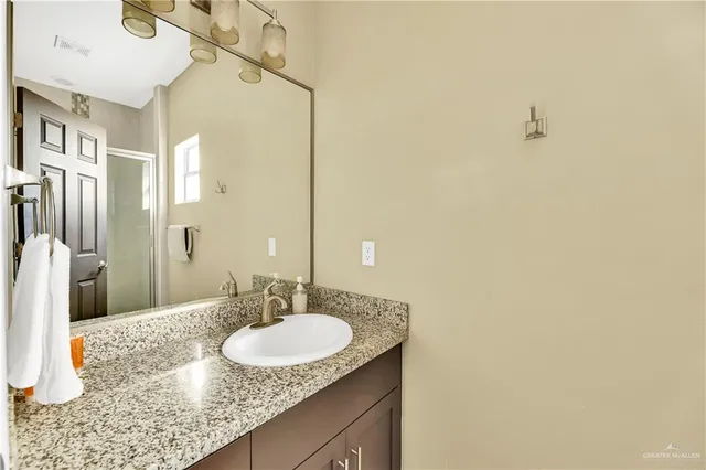 a bathroom with a granite countertop sink and a mirror