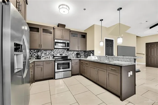 a kitchen with stainless steel appliances granite countertop a refrigerator a stove a sink and a oven