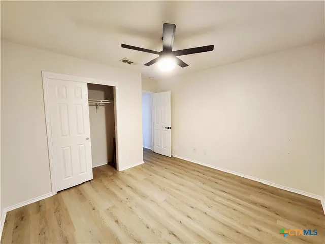 an empty room with a window and a ceiling fan