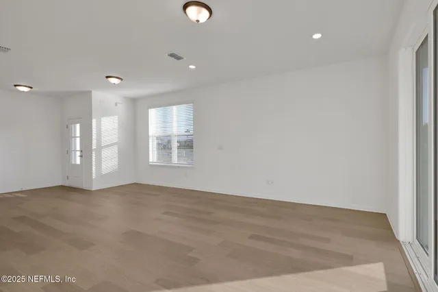 a view of an empty room with window and wooden floor