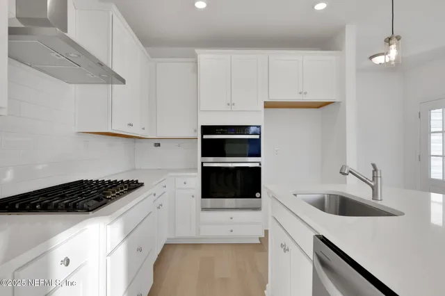 a kitchen with white cabinets a sink a stove and a refrigerator