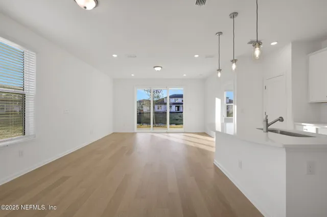 a view of an empty room with wooden floor and windows