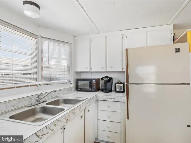 a white kitchen with sink and refrigerator