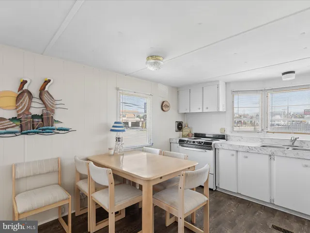 a kitchen with a dining table chairs stove and white cabinets