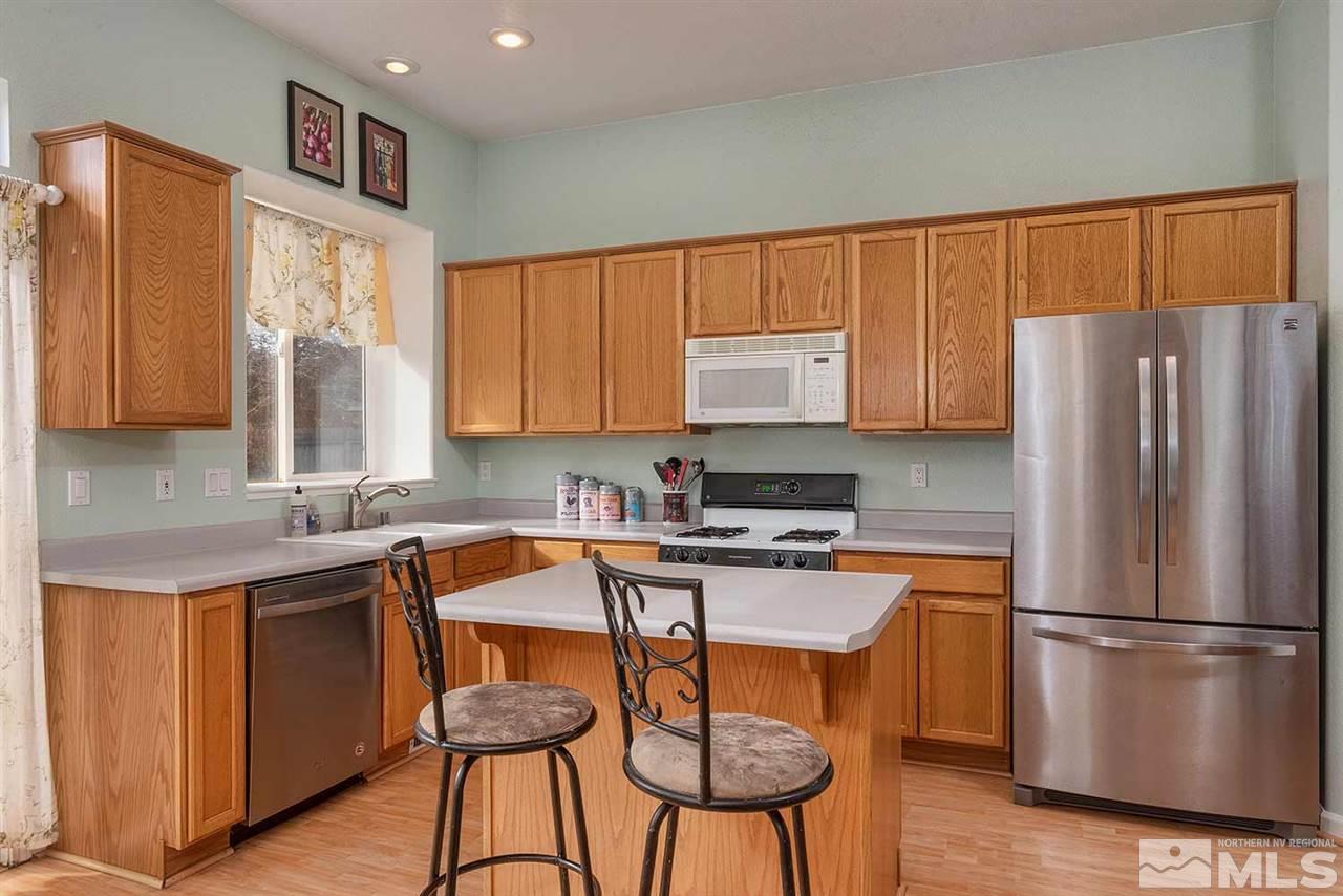 5540 Daybreak Drive Reno, NV 89523 - Photo 10 of 23 a kitchen with stainless steel appliances granite countertop a refrigerator a sink dishwasher and white cabinets with wooden floor