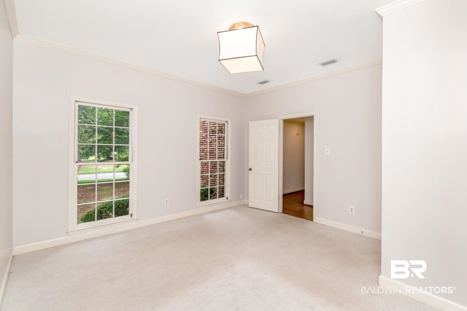 4776 Falls Church Road Mobile, AL 36608 - Photo 18 of 45 Carpeted interior space featuring two windows, crown molding, and a paneled door