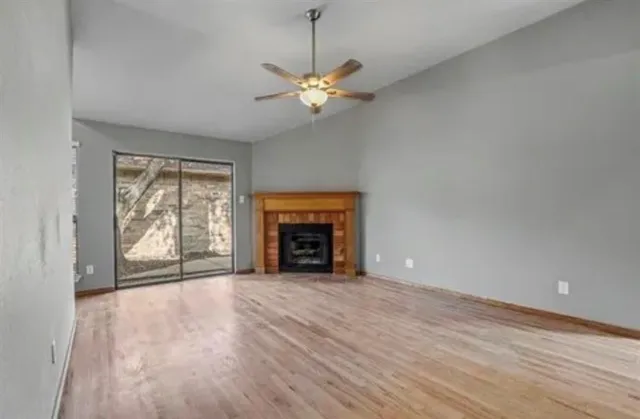 a view of an empty room with window and chandelier fan