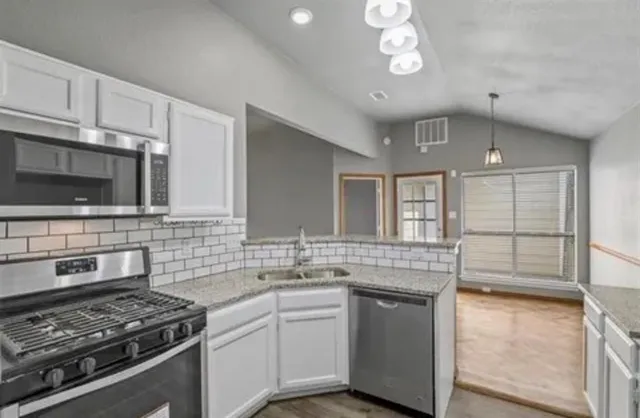 a kitchen with stainless steel appliances a stove sink microwave and cabinets