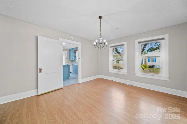a view of an empty room with window and wooden floor