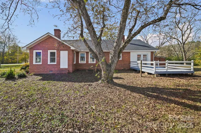 a front view of a house with a yard and large tree