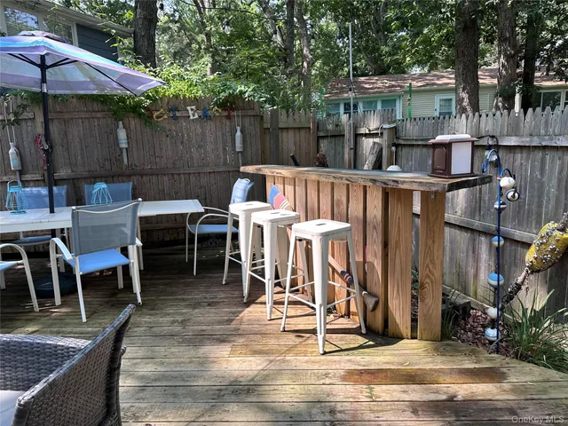 a view of a patio with table and chairs under an umbrella with wooden fence