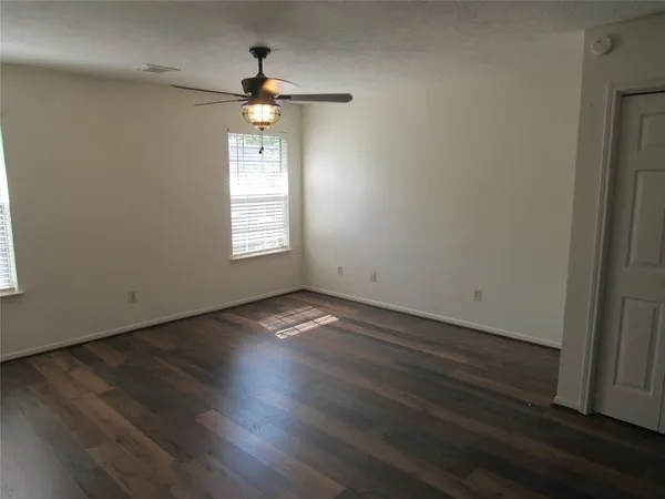 an empty room with wooden floor and windows