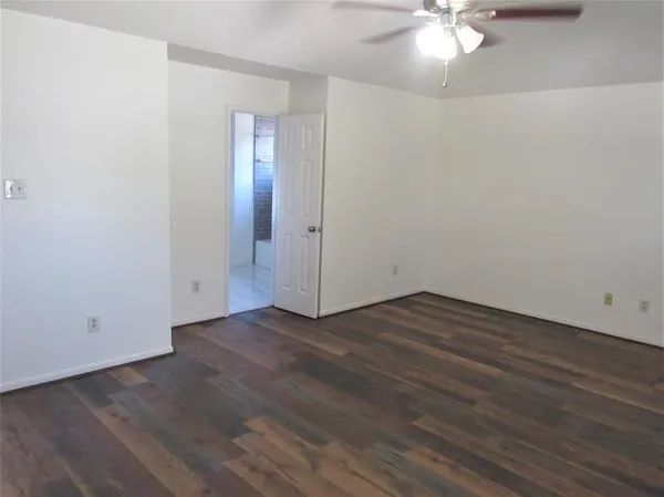 an empty room with wooden floor and fan