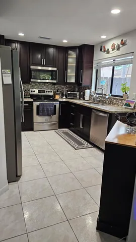 a kitchen with stainless steel appliances kitchen island granite countertop a stove a sink and a microwave