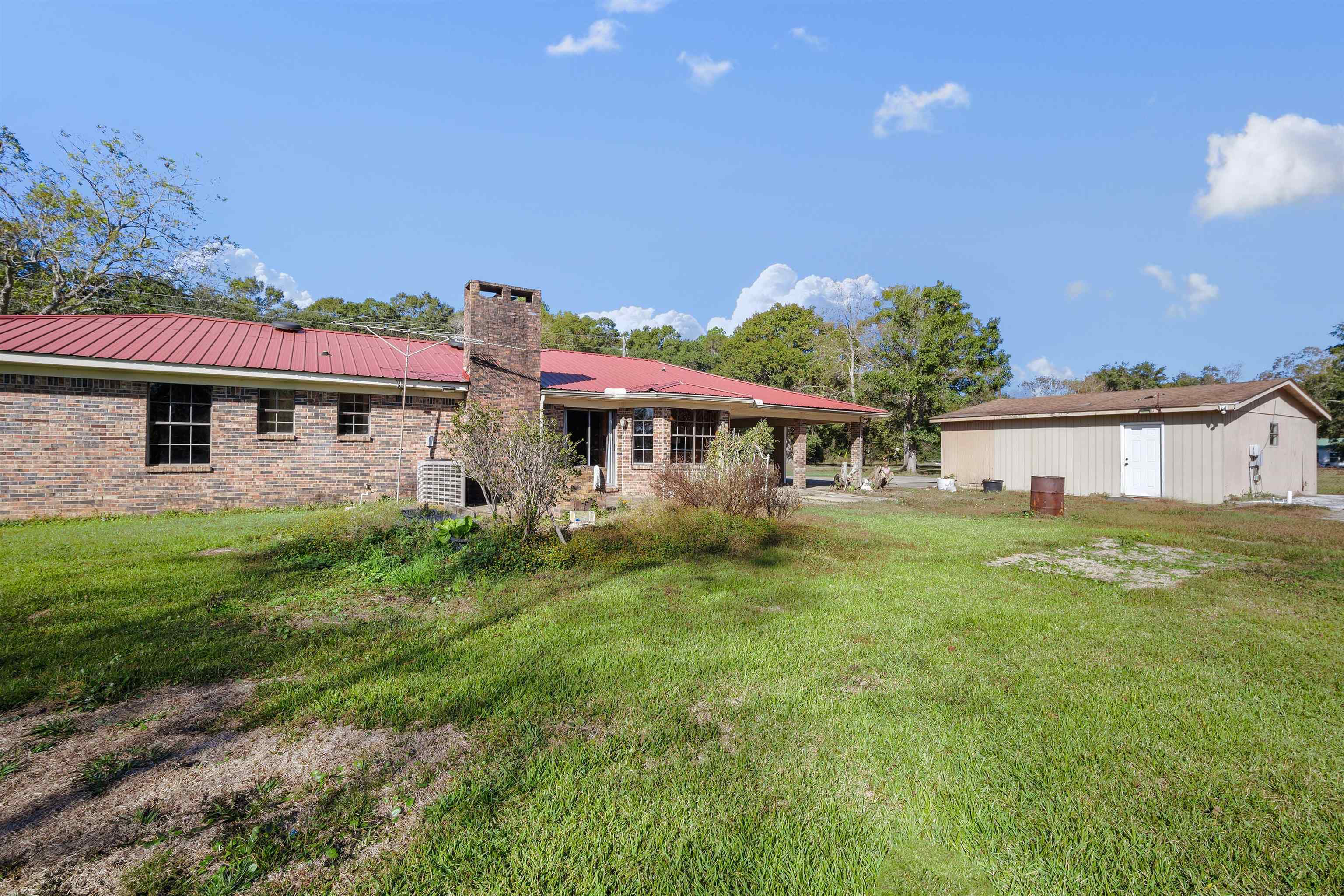 10285 Argyle Road Irvington, AL 36544 - Photo 24 of 28 Back of property with a yard, a metal roof, a chimney, an outbuilding, and brick siding