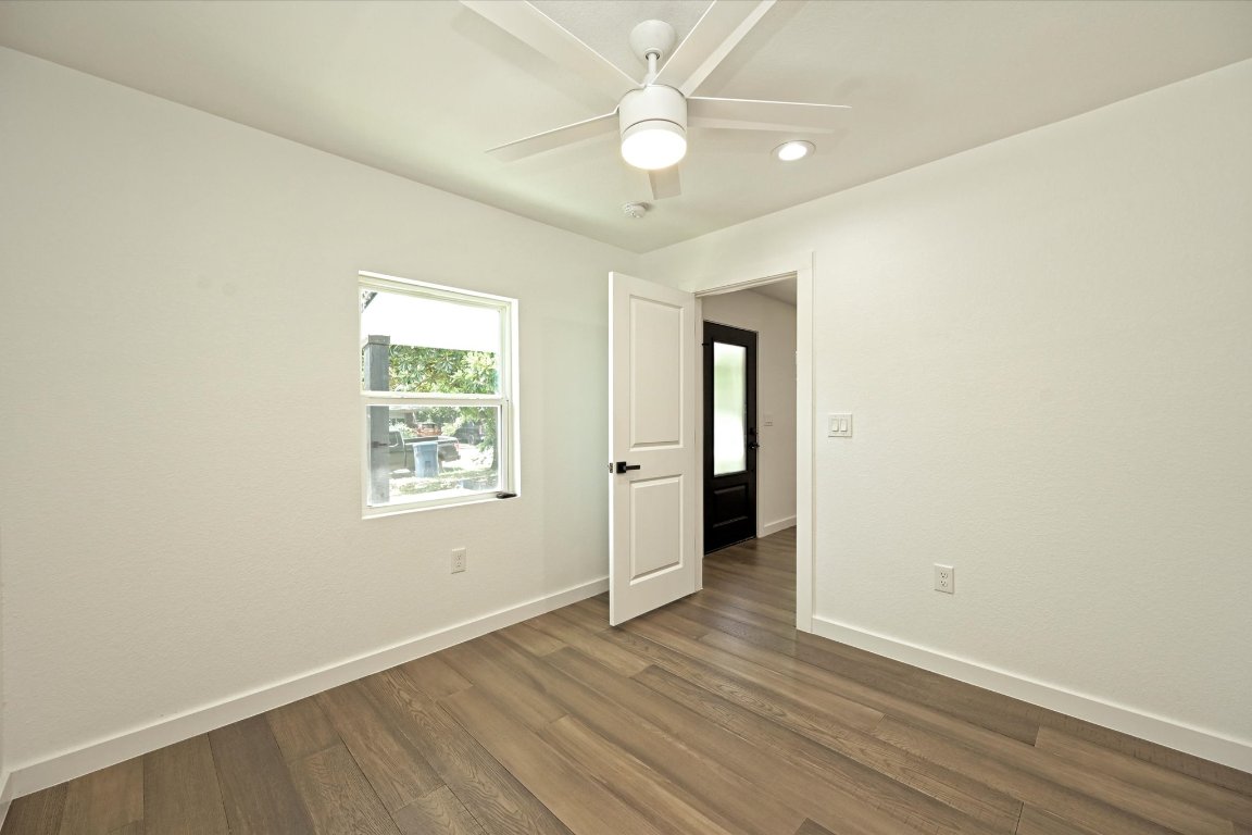 710 East 2nd Street Elgin, TX 78621 - Photo 22 of 30 an empty room with wooden floor ceiling fan and windows