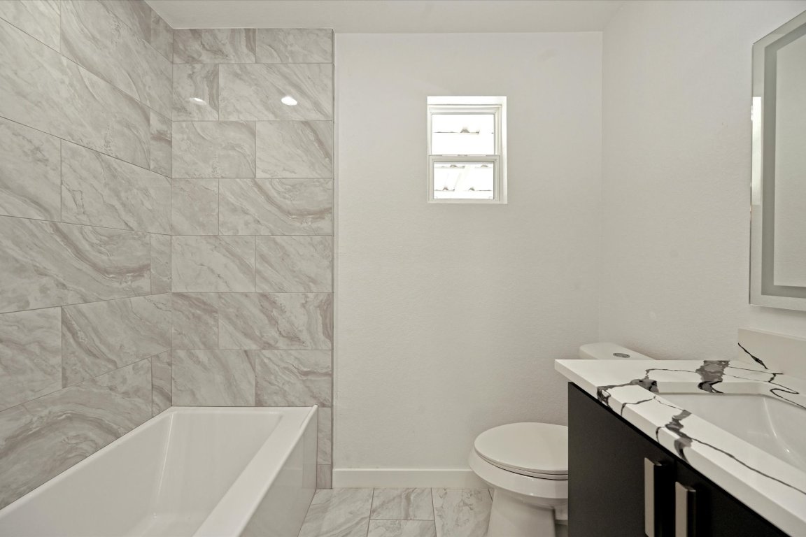 710 East 2nd Street Elgin, TX 78621 - Photo 24 of 30 a bathroom with a granite countertop toilet a sink and a bathtub