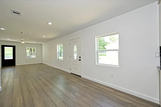 an empty room with wooden floor and windows