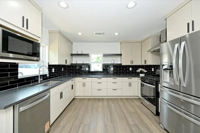 a kitchen with stainless steel appliances granite countertop a stove a sink and a refrigerator