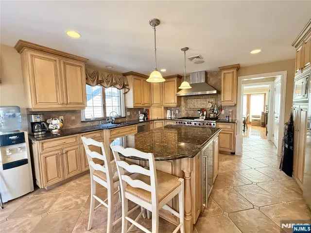 a kitchen with stainless steel appliances granite countertop a sink a stove a refrigerator cabinets and chairs