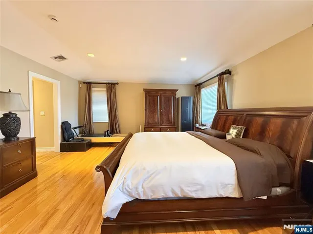 a spacious bedroom with a bed and wooden floor