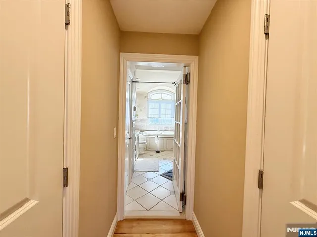 a view of a hallway with wooden floor and a bathroom