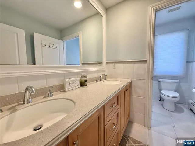 a bathroom with a granite countertop sink and a toilet