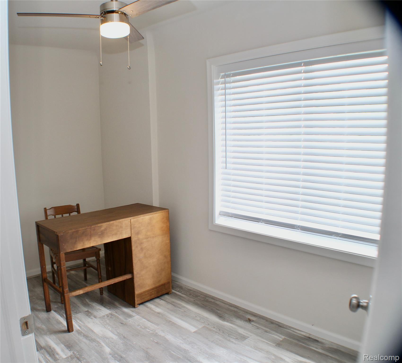 48677 Sugarbush Road, Unit 1 New Baltimore, MI 48047 - Photo 6 of 10 Bright room featuring a large window with white blinds, wood-finish flooring, and a ceiling fan with integrated lighting