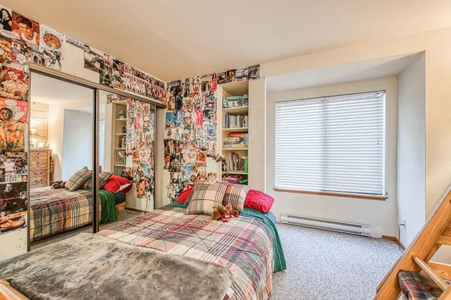 a bedroom with a bed a flat screen tv and a window