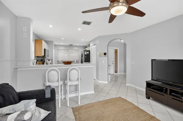 a living room with furniture a flat screen tv and kitchen view