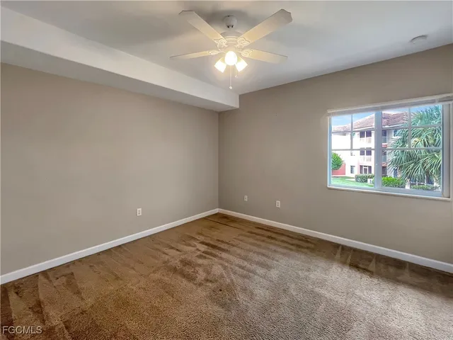 an empty room with a window and a fan