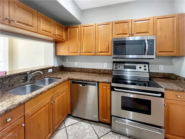 a kitchen with granite countertop a sink stainless steel appliances and cabinets