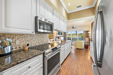 a kitchen with stainless steel appliances granite countertop a refrigerator a stove and a sink with wooden floor