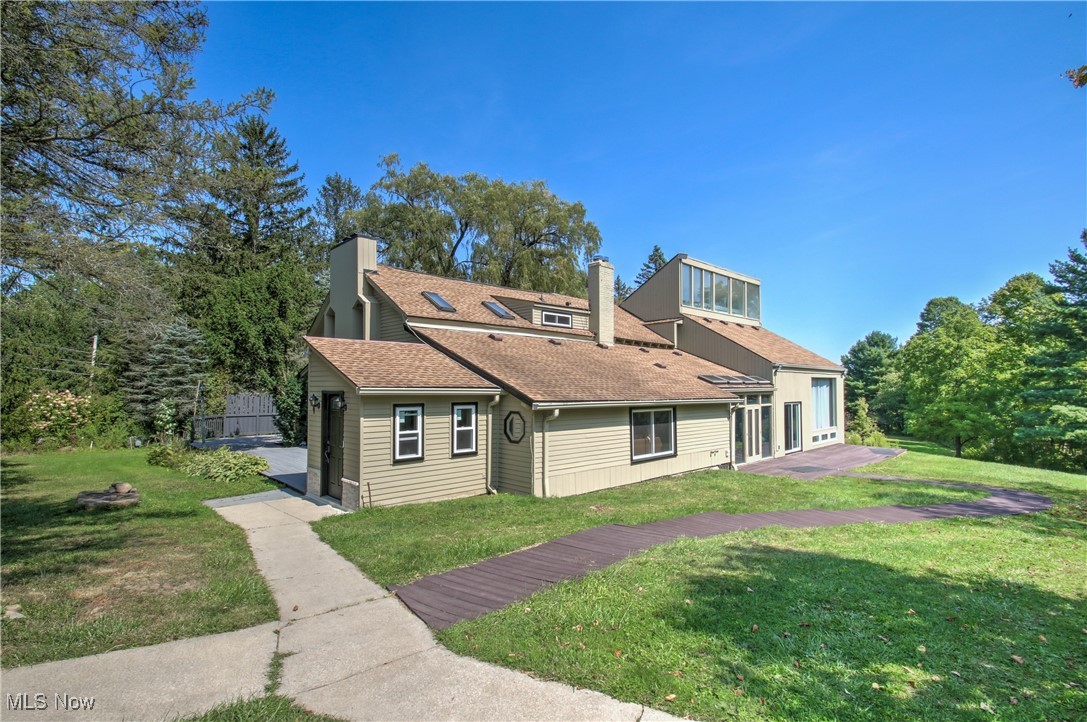 View of front facade with a front yard, a chimney, and roof with shingles
