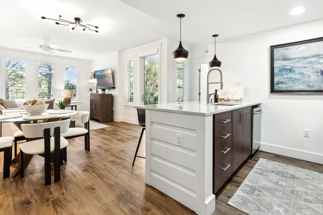 a kitchen with stainless steel appliances kitchen island granite countertop a stove a sink a dining table and chairs with wooden floor