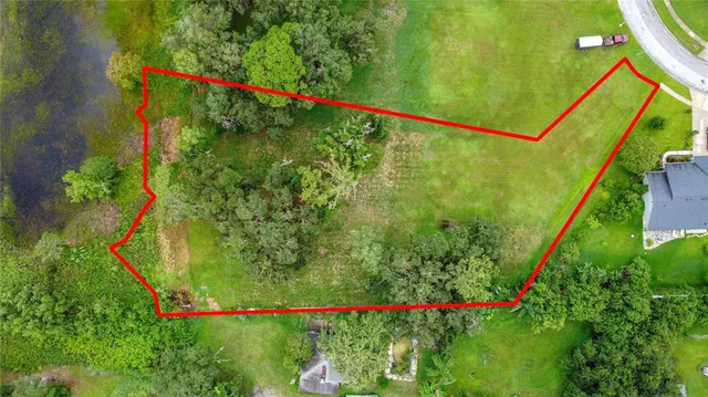 an aerial view of residential houses with outdoor space and trees