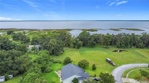 a view of a house with a big yard and large trees