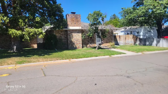a view of a house with a yard and large tree